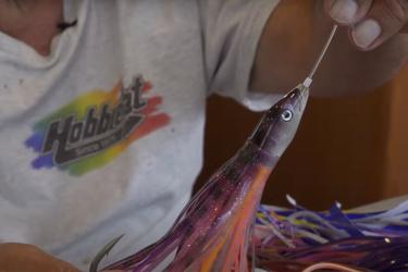 A close-up photo of a fishermen holder a colorful fishing lure.