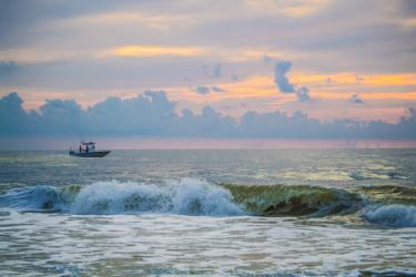 dam-migration-miss/md_kLR8jNS2lBr3.jpg Landscape photo of ship on the water with cloudy pinkish orange sky in the background.