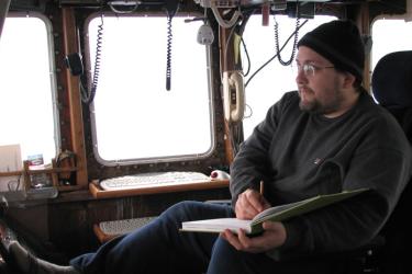 biologist on a boat recording data in a field book