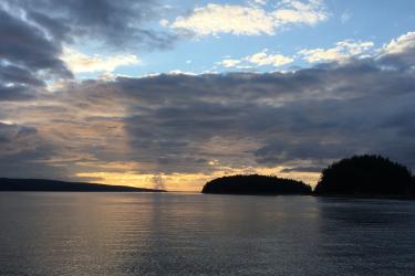 sunset on the ocean with islands in the distance.