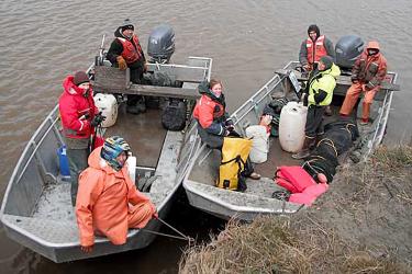 Two boats filled with scientists wearing coats
