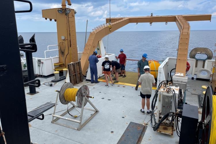 6 people in hard hats work on the deck of a ship