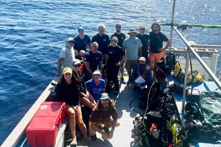 Group of people aboard a vessel smiling for the camera