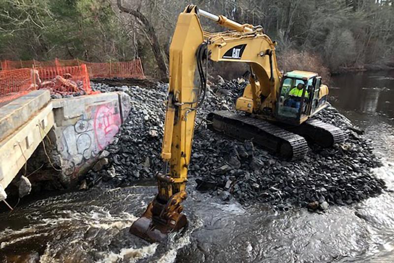 An excavator demolishing a dam.
