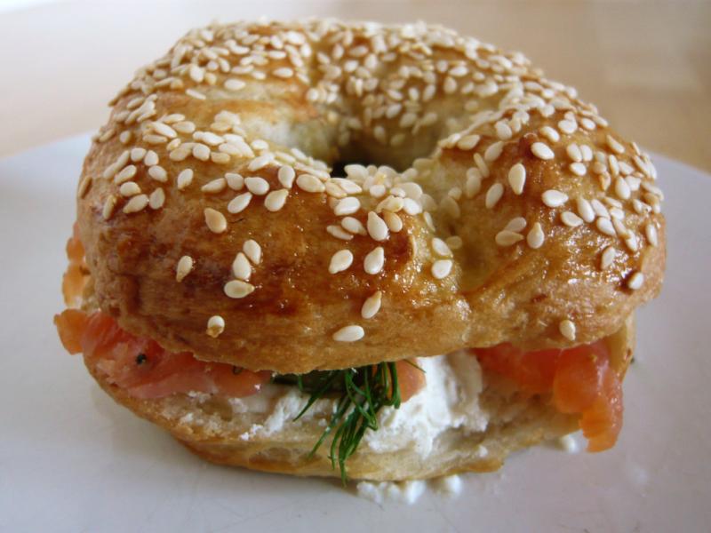Photo of a sesame bagel sandwich with lox and schmear. 