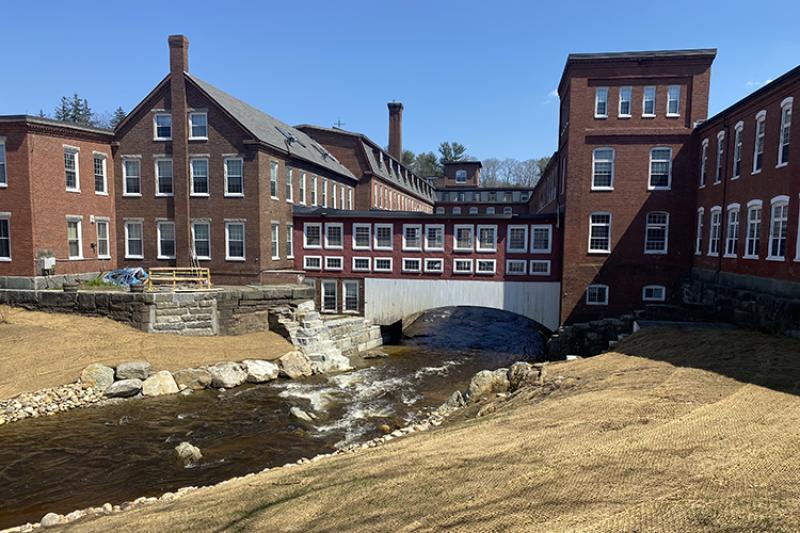 A river runs under a bridge and between several buildings
