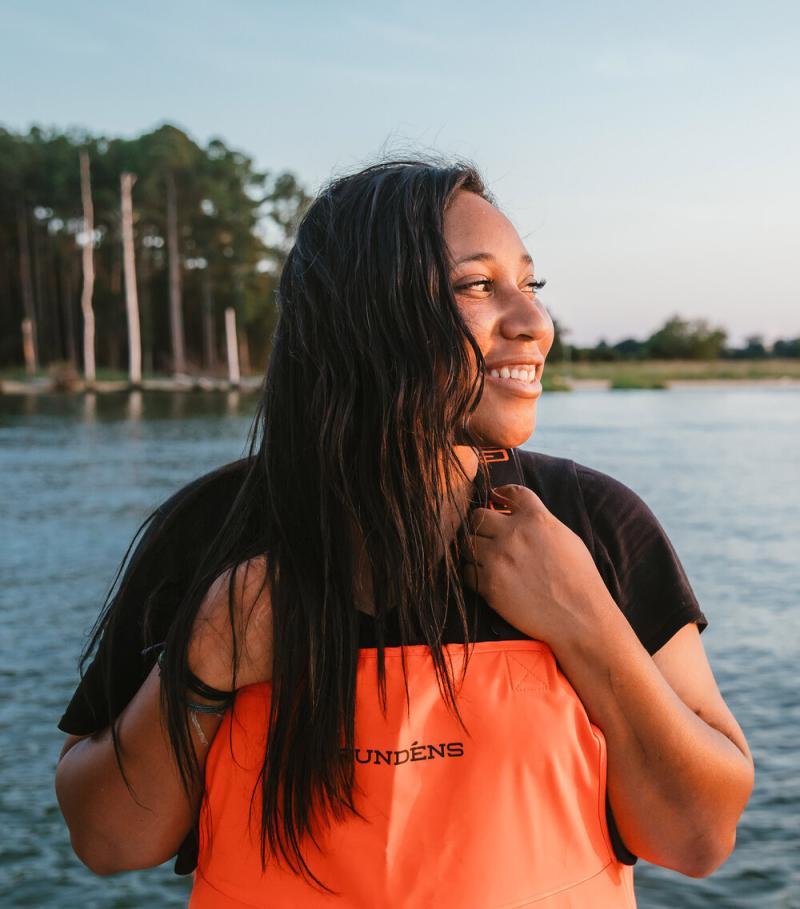 A photo of Imani Black wearing waders and looking out across the water.