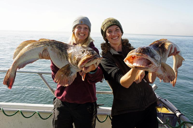 two women each holding a lingcod