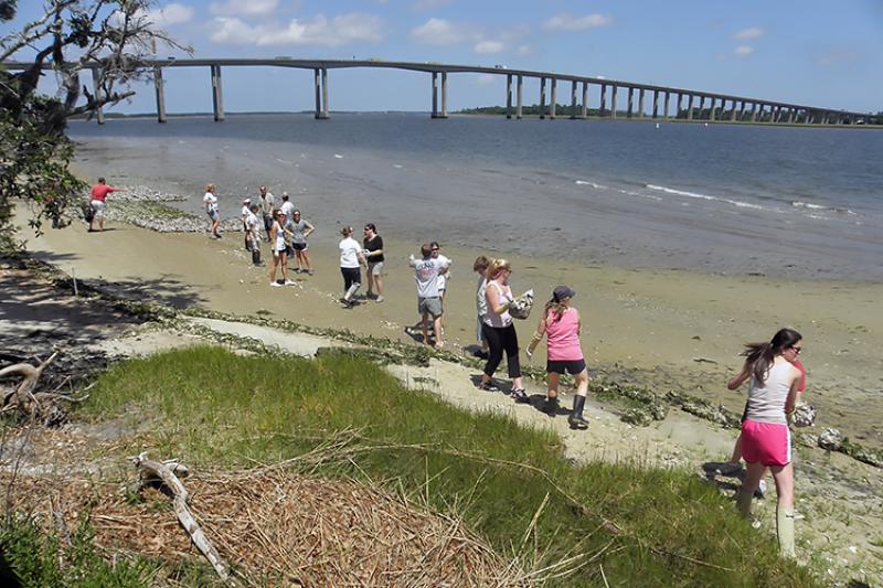 Volunteers standing along the shoreline and passing bags of oysters down the line to help construct a living shoreline