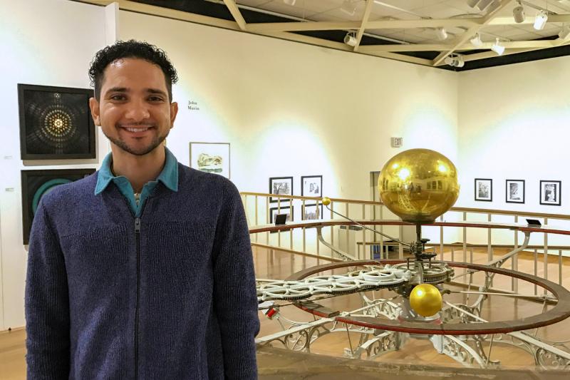 Science writer standing in front of a solar system installation in a musuem.