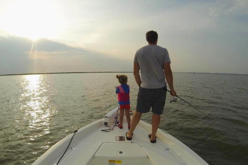 Man and child fishing off boat
