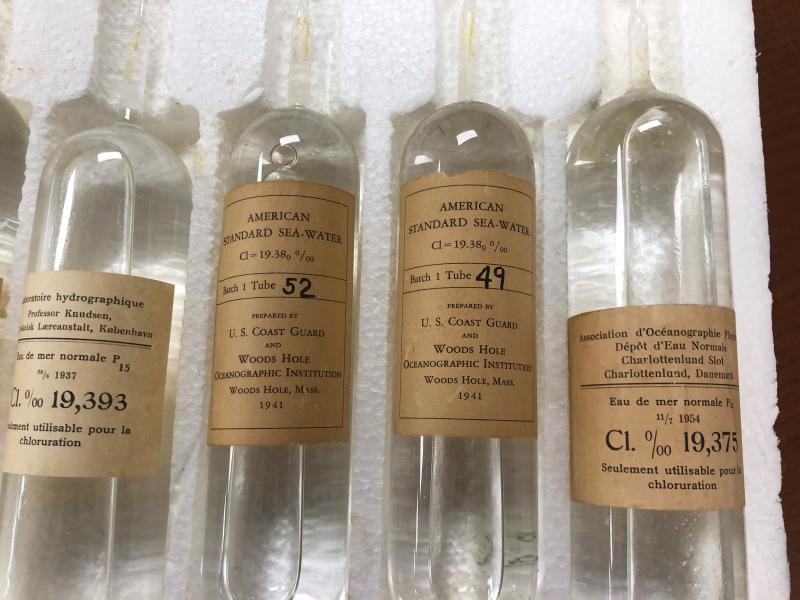 Close-up photo of 4 glass vials, or ampoules, of standard water from Denmark (1937 and 1954) and Woods Hole (1941)in a styrofoam holder