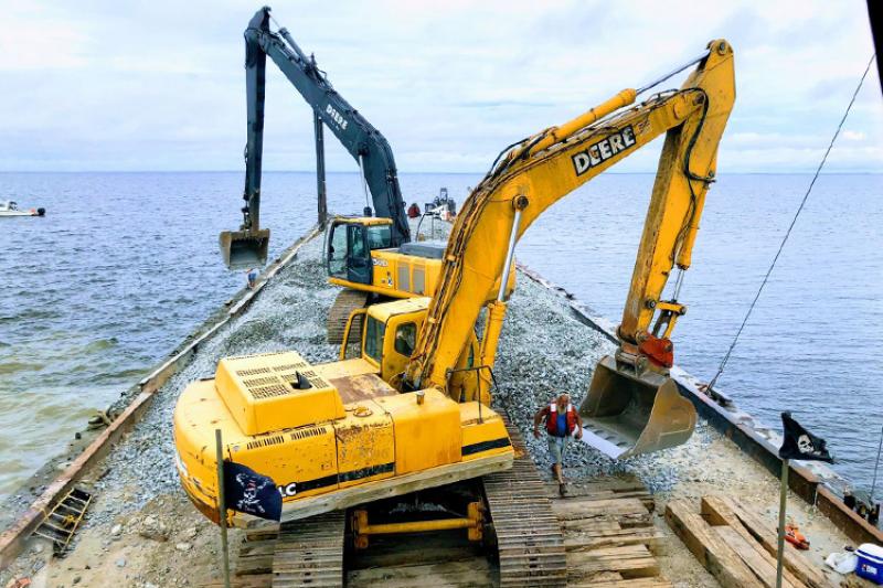 Two excavators on a barge floating in the water
