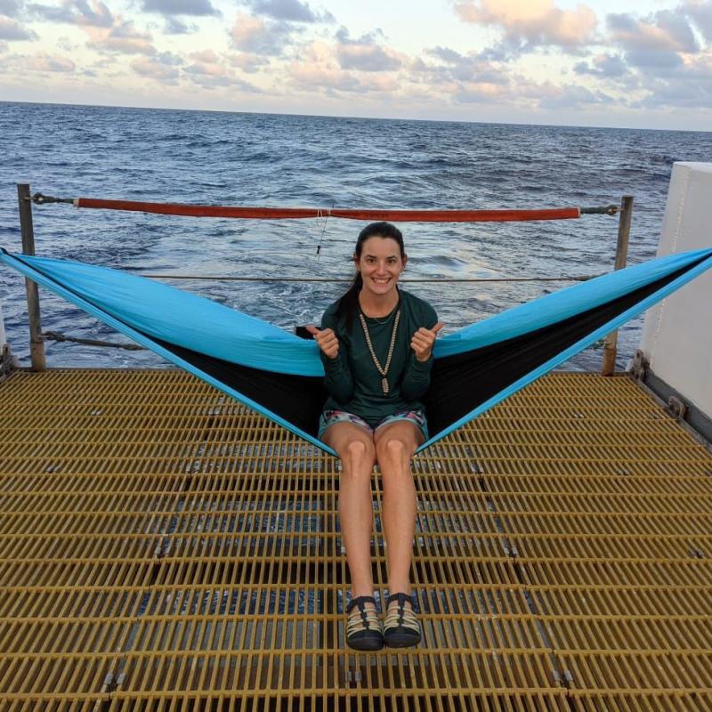 Mary Applegate sitting on a hammock set up on the aft deck of a ship.