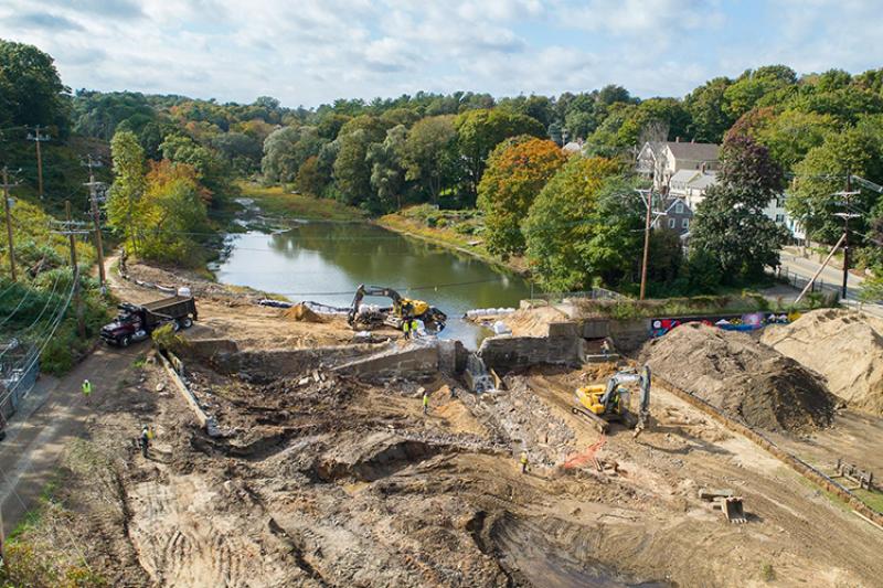 Aerial view of construction equipment removing a dam from a stream