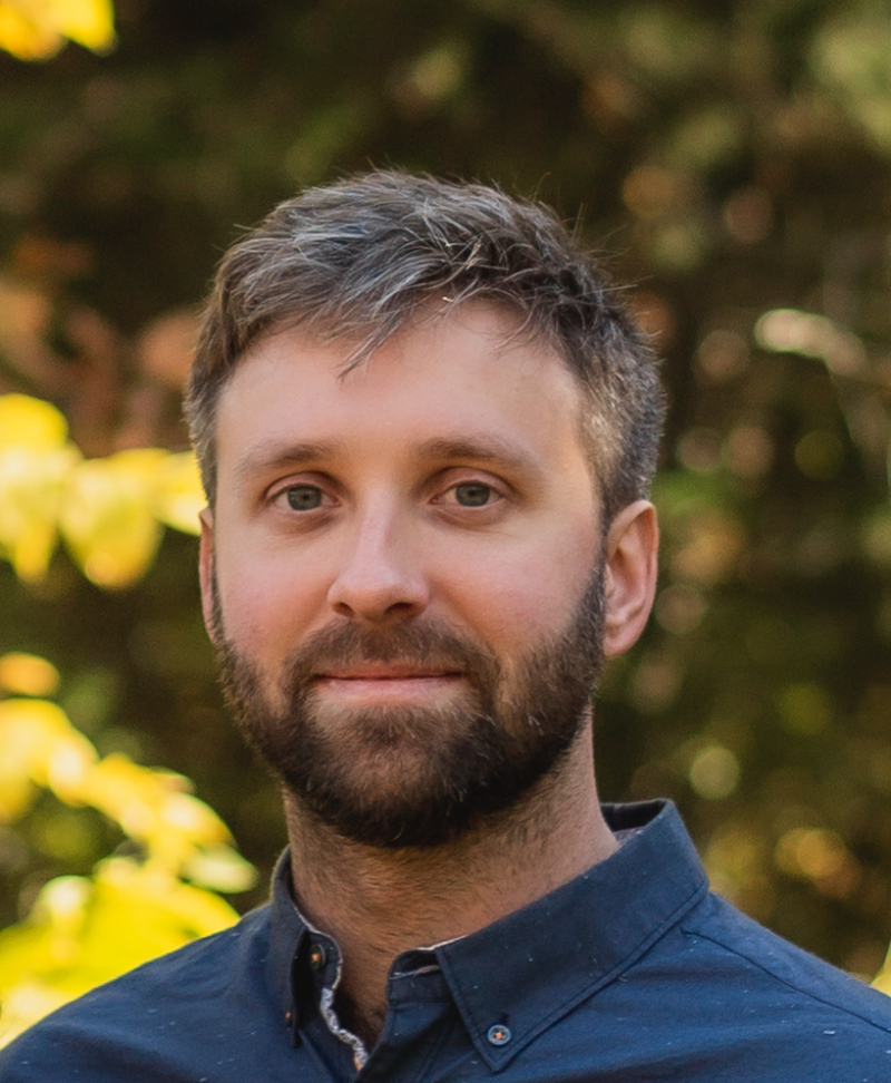 Male scientist stands in front of outdoor background