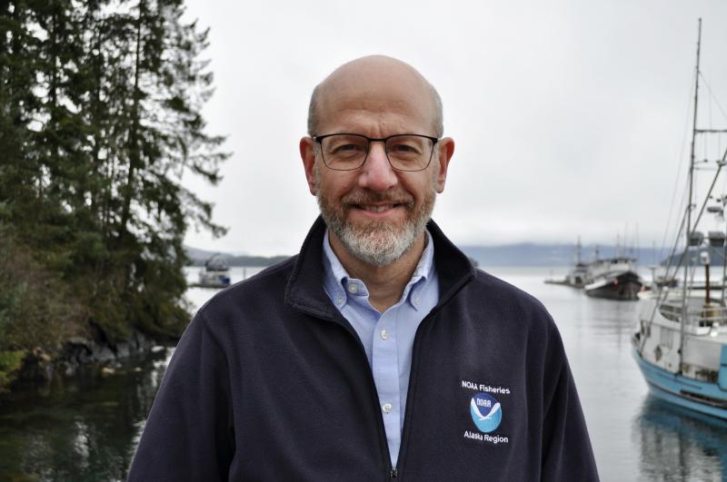 Jon Kurland posing for his headshot with trees, water, and boats in the background