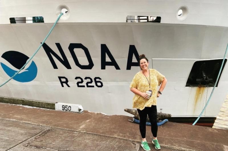 Jamie Clark stands in front of the Pisces NOAA ship