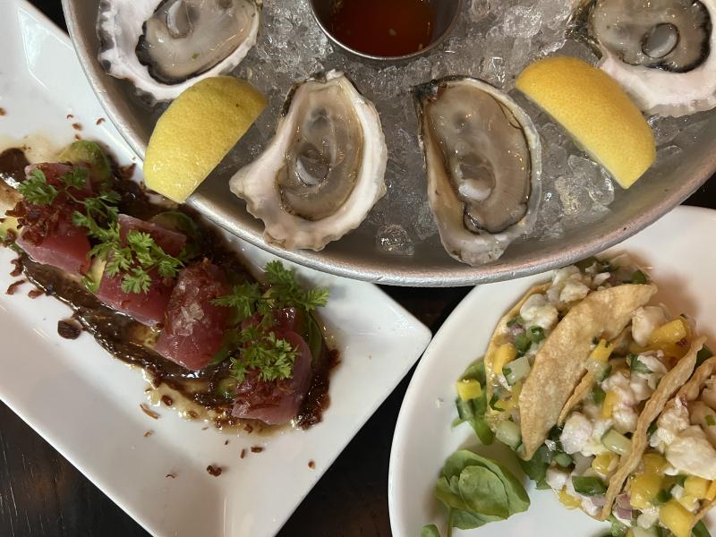 Neatly plated tuna crudo, halibut ceviche tacos, and eastern oysters, served at Row 34 restaurant.
