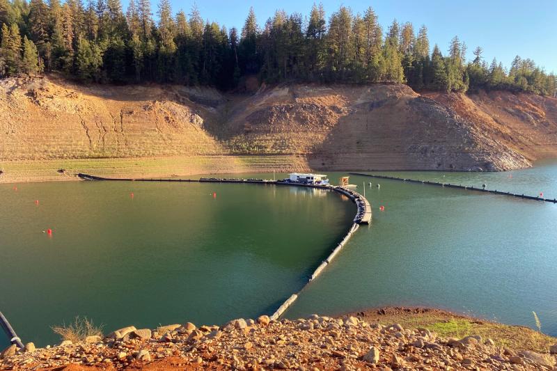 Shasta Reservoir seen from the shore with a floating structure extending to the other shore