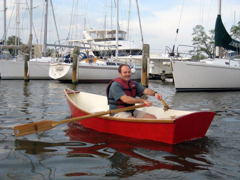 a man in a red boat rows in a small harbor. 