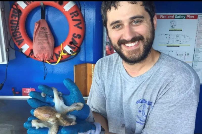 Andy Ostrowski holding an octopus on a research survey