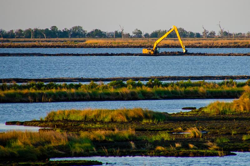 Equipos de construcción en una estrecha franja de tierra en un humedal