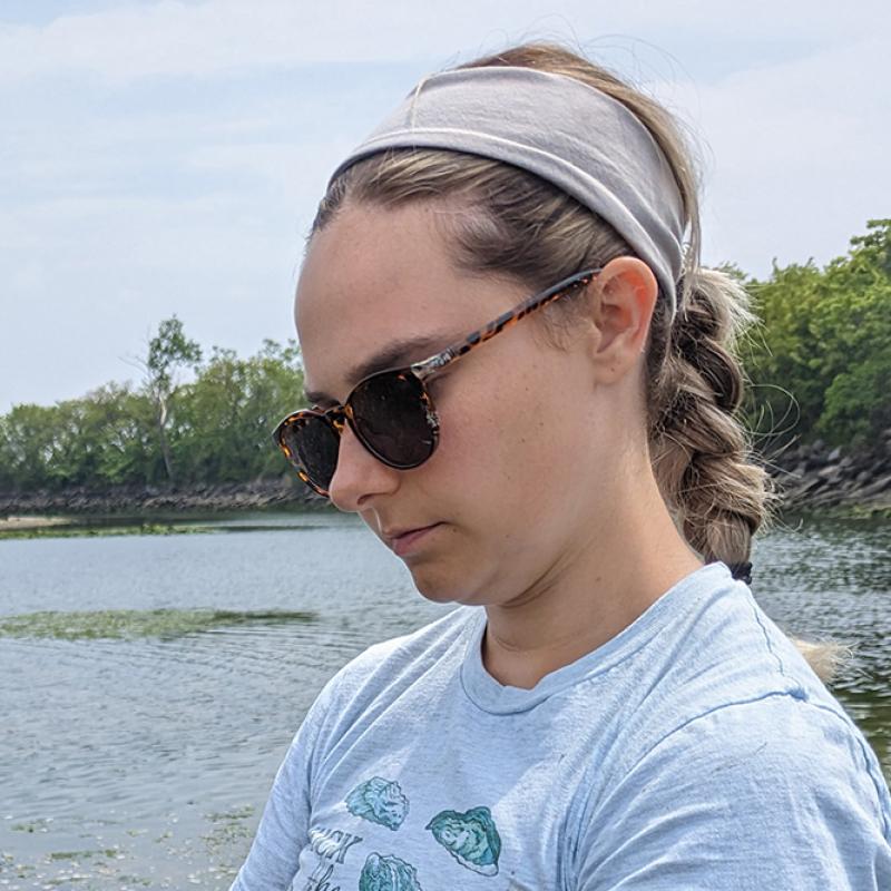 Mariah Kachmar at an oyster bed in sungalsses and t-shirt.