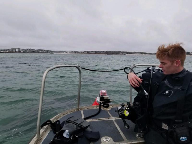 Alex Creed checking dive gear in bow of boat.