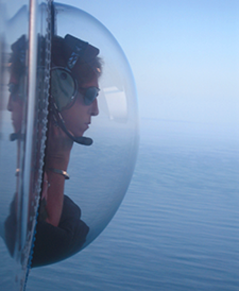 Woman looking out of convex window at sea