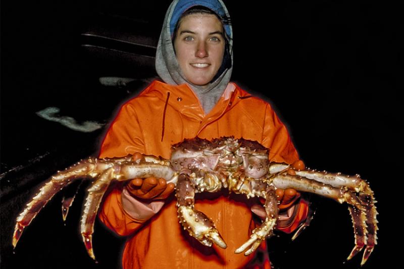 Scientist in orange coat holding a large crab