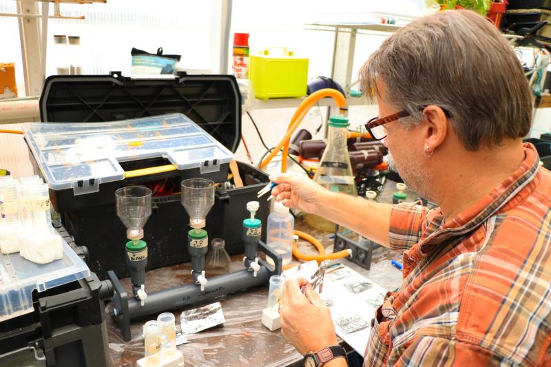 Filtering water samples in the biodeposition- experiment.  Tool boxes and samples on work bench, with filters and samples.