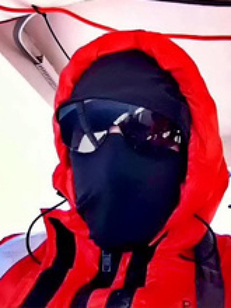 Man wearing black face mask and an orange coat with a hood