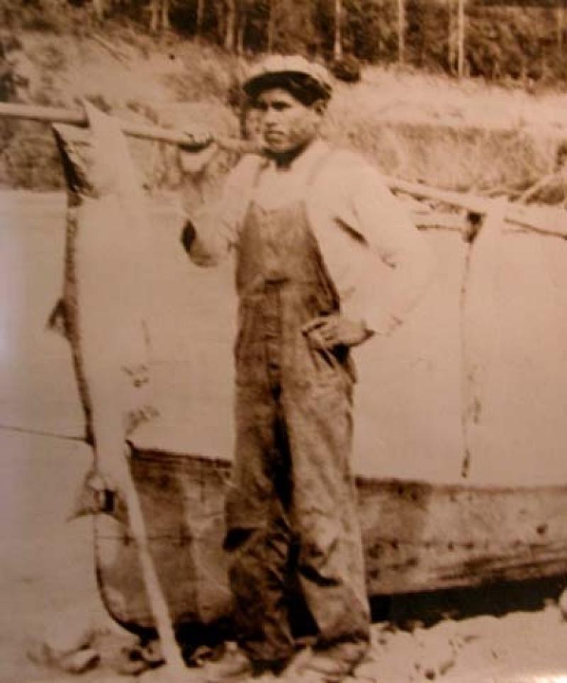 Man carrying a fish on a stick over his shoulder