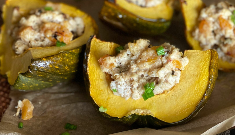 a quartered acorn squash hollowed out and stuffed with a grab mixture.