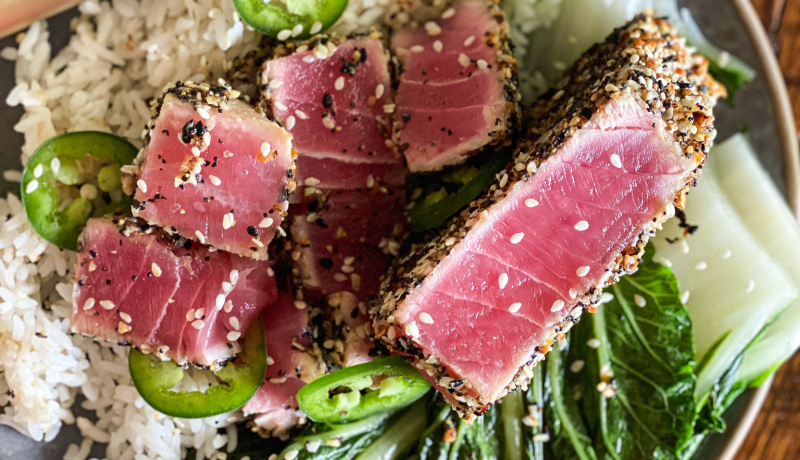 A plate of white rice, sliced jalapenos, bakchoy, and slices of seasoned and seared tuna.